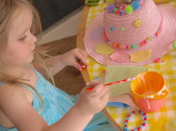 Lovely Easter Bonnet DIY by a Little Girl. I just can’t believe my eyes. The lovely girl can DIY such a beautiful craft all by herself. She is trying to stick the pattern around the brim and add the beading and pom poms to decorate her bonnet for the girls Easter bonnet competition at her school.