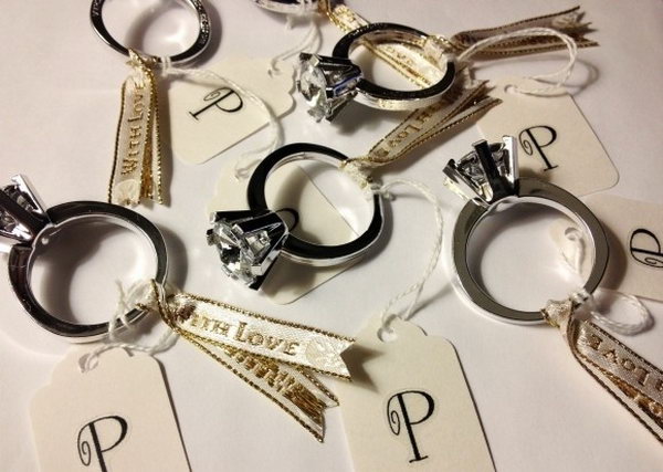 Costume Engagement Ring Favors. These costume engagement rings can be done with 2 simple steps. Fold the ribbon around the ring and twist to secure it. Add the personalized tag by writing names of each guests. You can also add some love swear or beautiful photos.