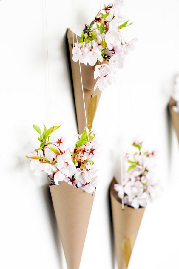 Blossoming Flower Cone Wall Display. Create cones from cardstock, punch 2 holes at both sides, take the string to hang the cone pointed side down. Arrange the cones on the wall and place some flowers in them to create the beautiful wall art for your dorm room.