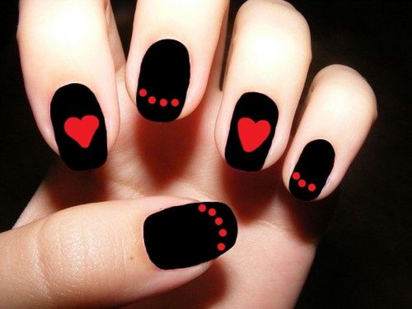 Diseño de uñas rojo y negro con corazones y puntos.