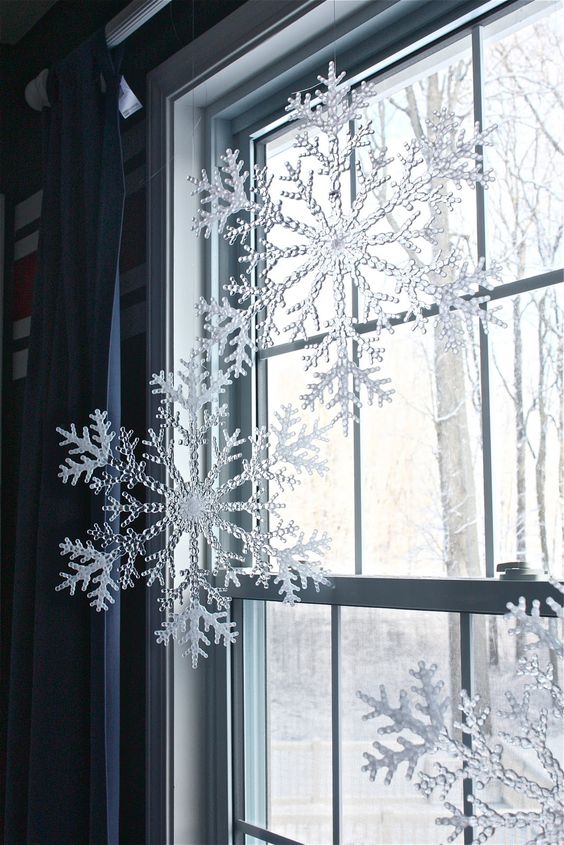 Plastic Snowflakes from Dollar Tree Hung from Curtain Rod with Fishing Wire. Make your home look festive for less this holiday season with easy DIY dollar store Christmas decor ideas. Wreaths, candles, centerpieces, wall art, ornaments, vases, gifts and more!